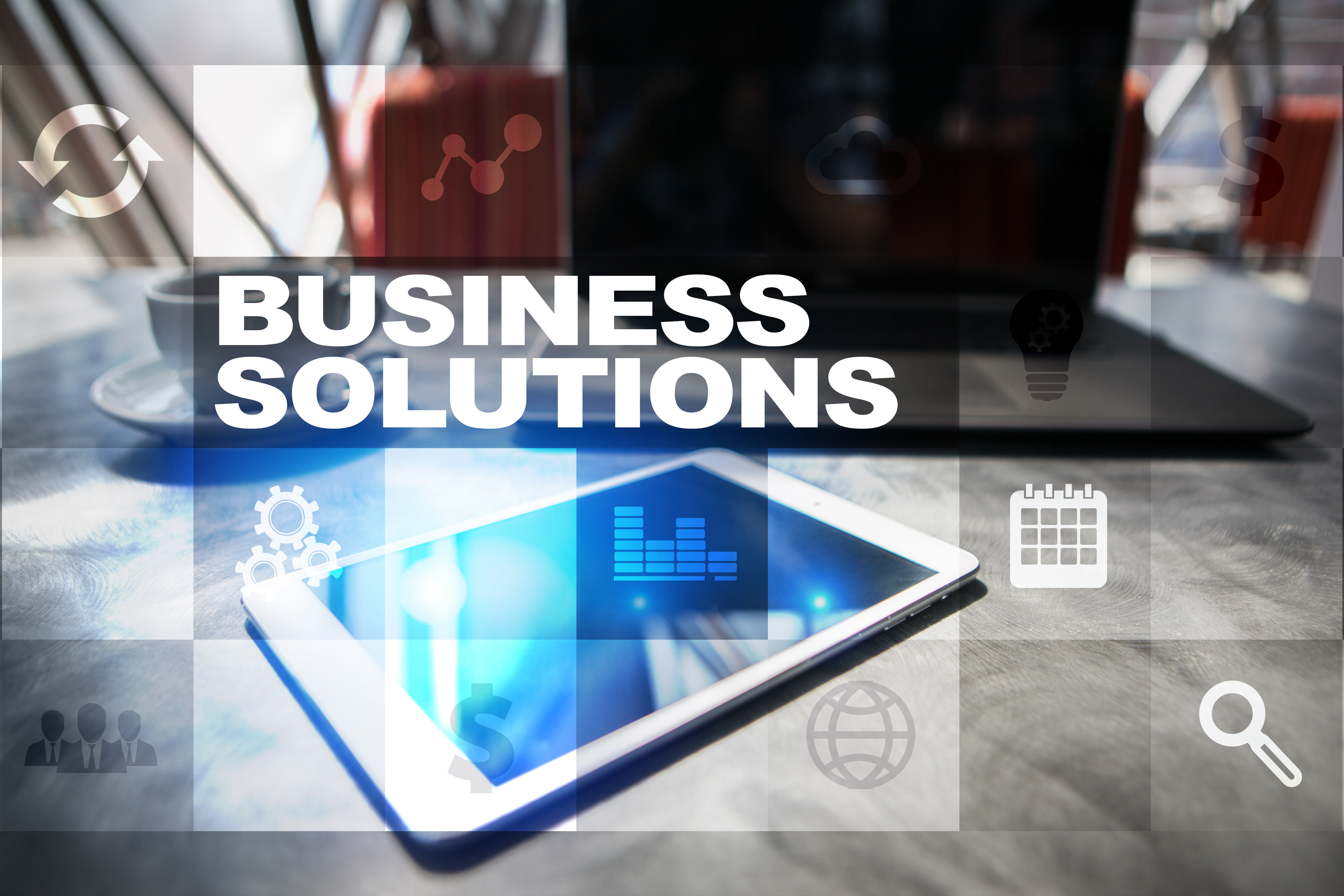 Tablet and laptop on a desk overlaid with business systems icons